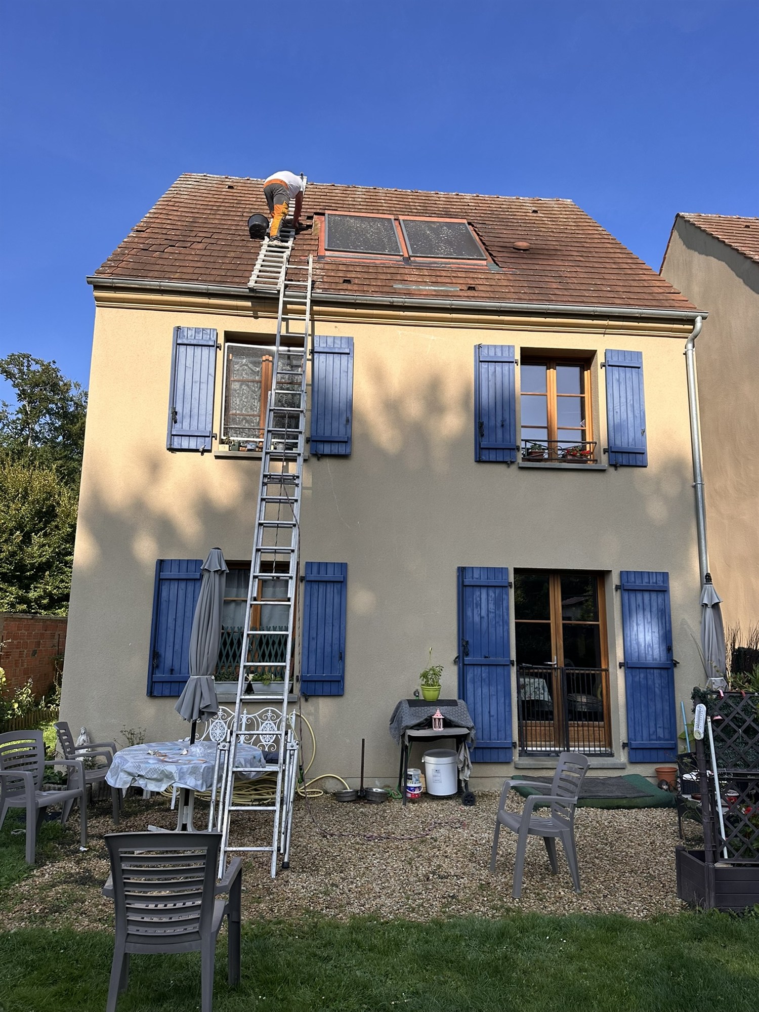 Couvreur travaillant sur une toiture en tuiles près de panneaux solaires