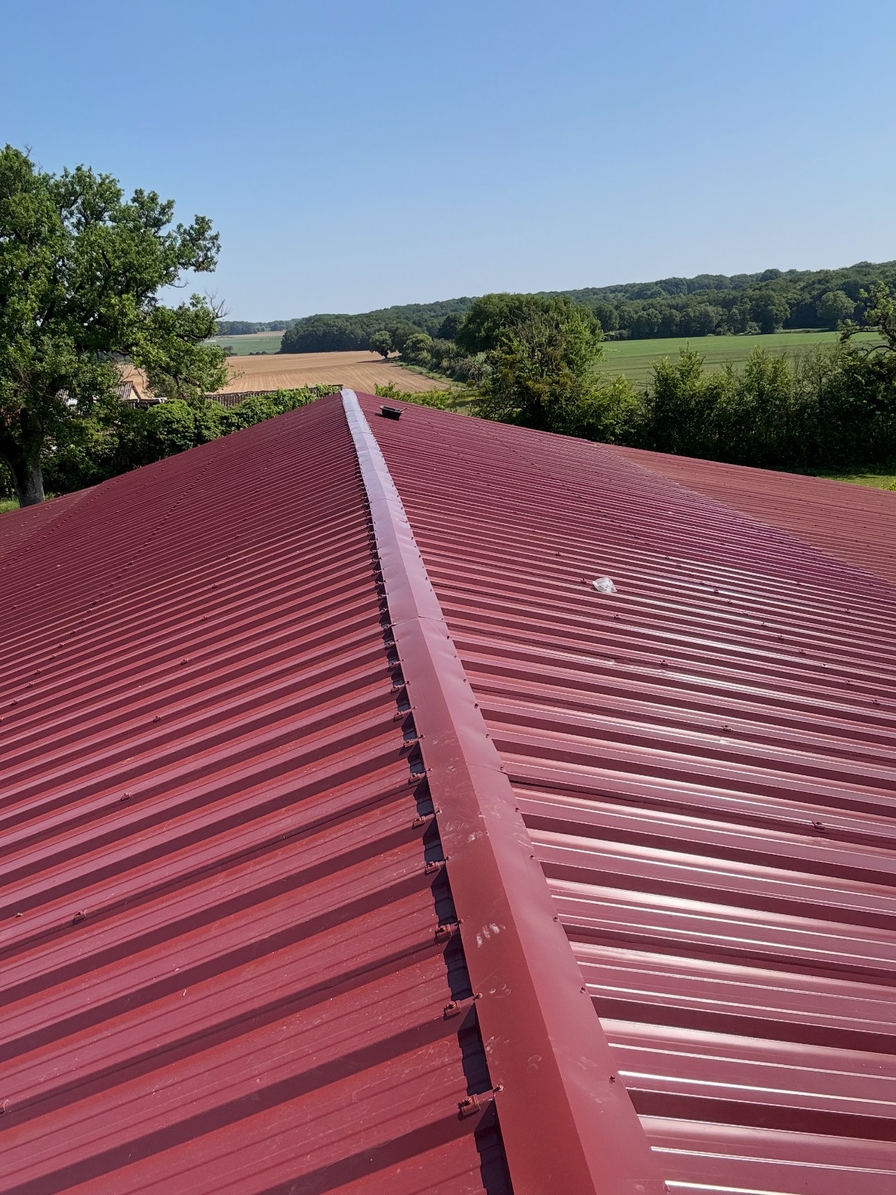 Nouvelle toiture en bac acier rouge posée sur le bâtiment agricole