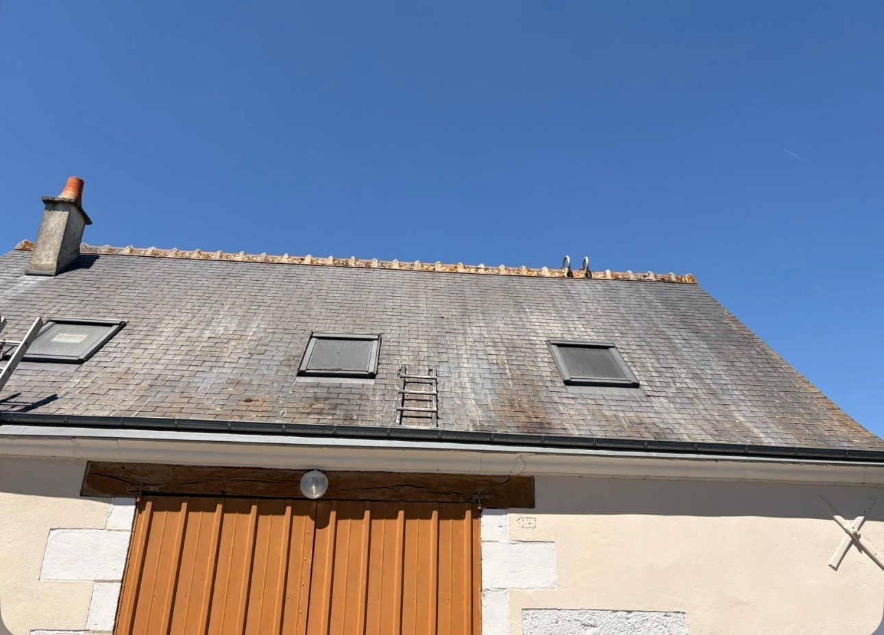 Toiture ardoise grise tachée de mousse et de lichen avant nettoyage